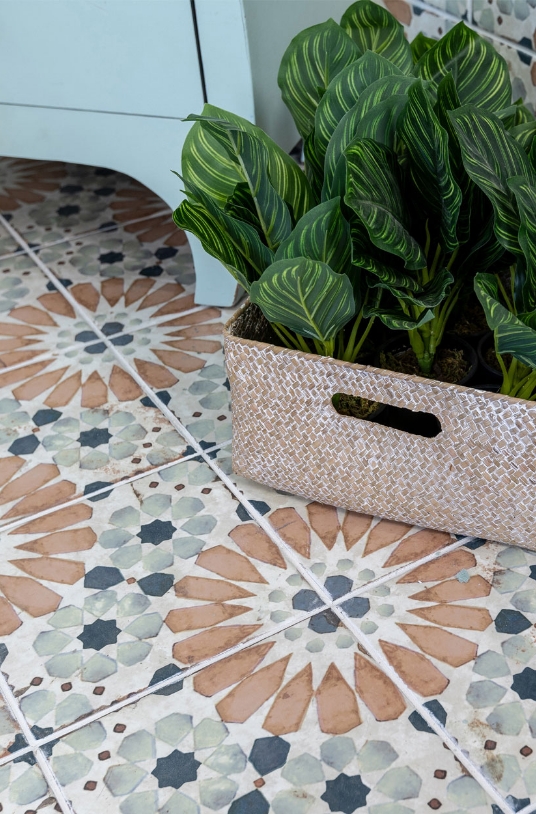 Decorative mosaic tile floor with a potted plant in a textured basket.