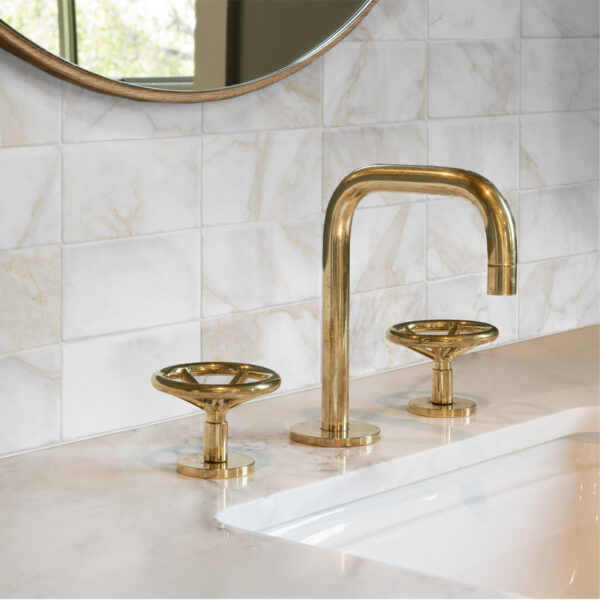 A bathroom sink with gold fixtures and marble counter.