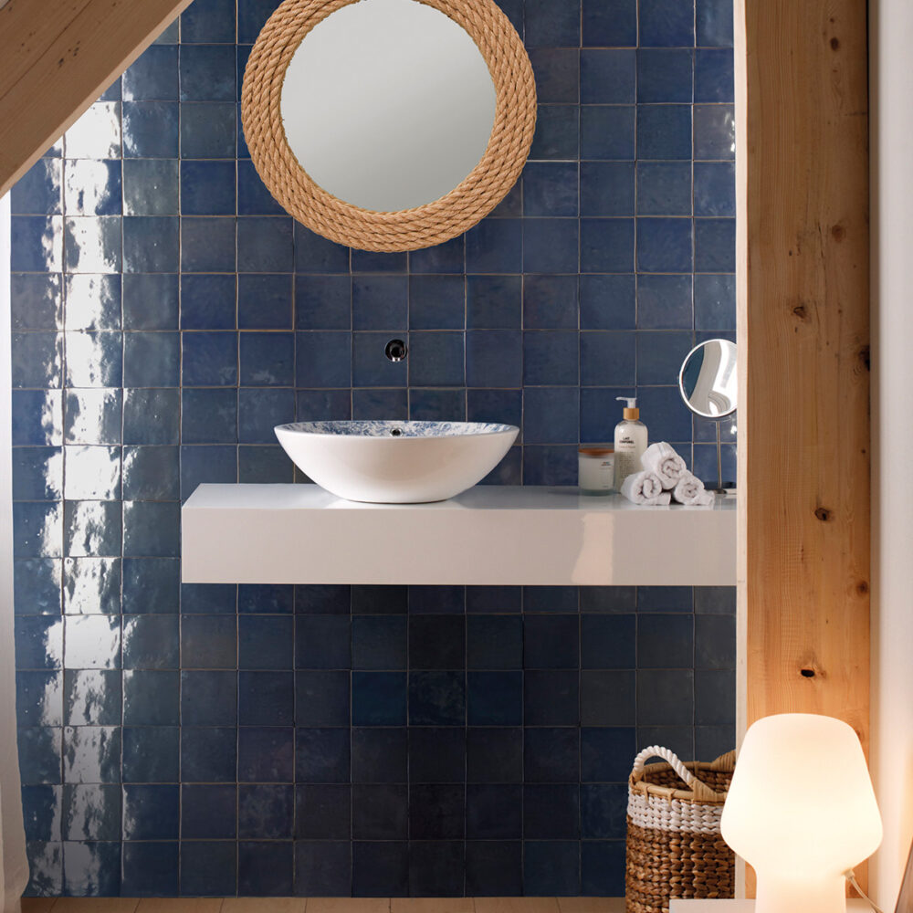 A bathroom with blue tile and wood accents.