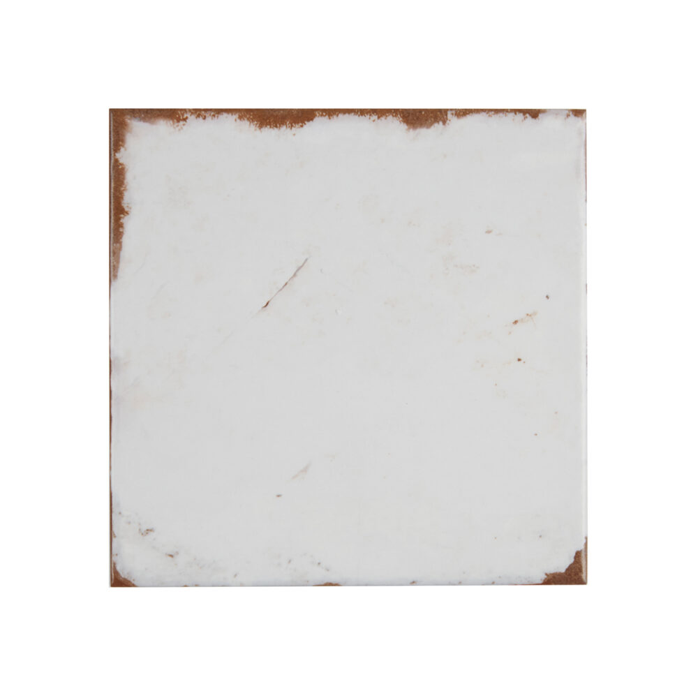 A white tile with brown grout and some rust