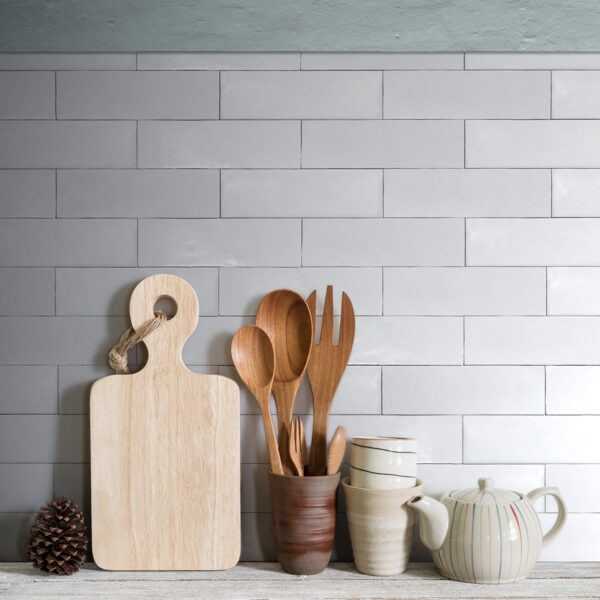 A kitchen counter with wooden utensils and cups.