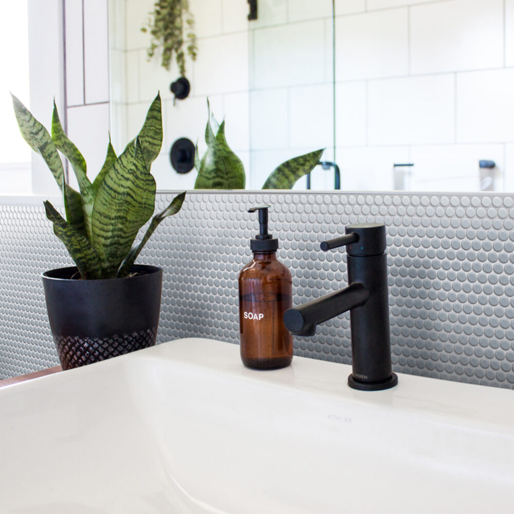 A bathroom sink with a plant in the corner.