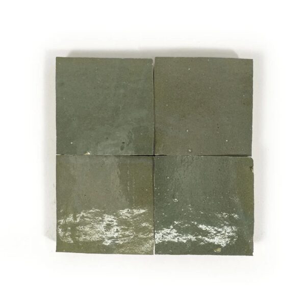 A square of green tile sitting on top of a white surface.